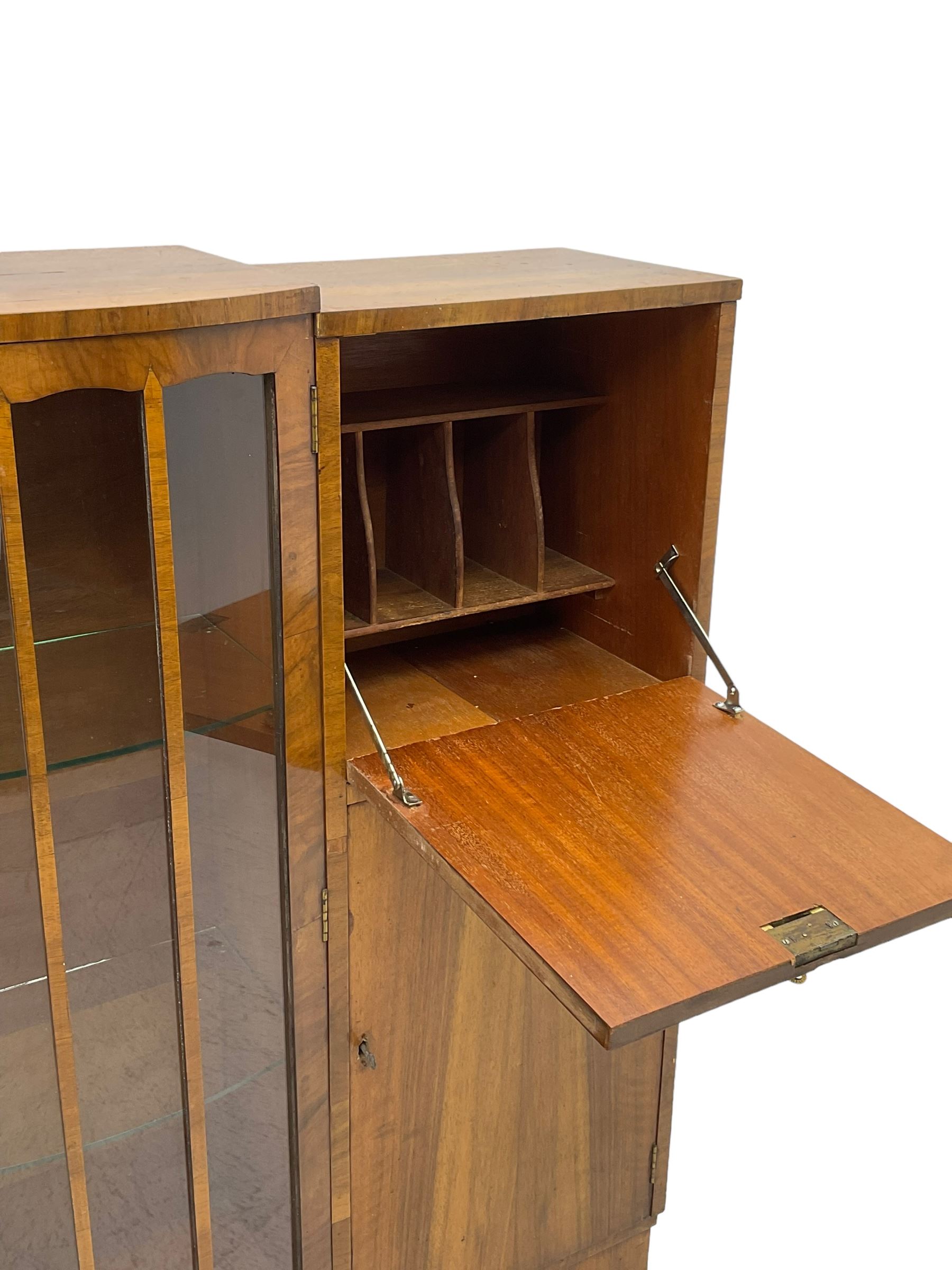 Early 20th century walnut side cabinet, enclosed by central bowed and glazed door, fitted with drawer, two cupboards and fall front, on plinth base