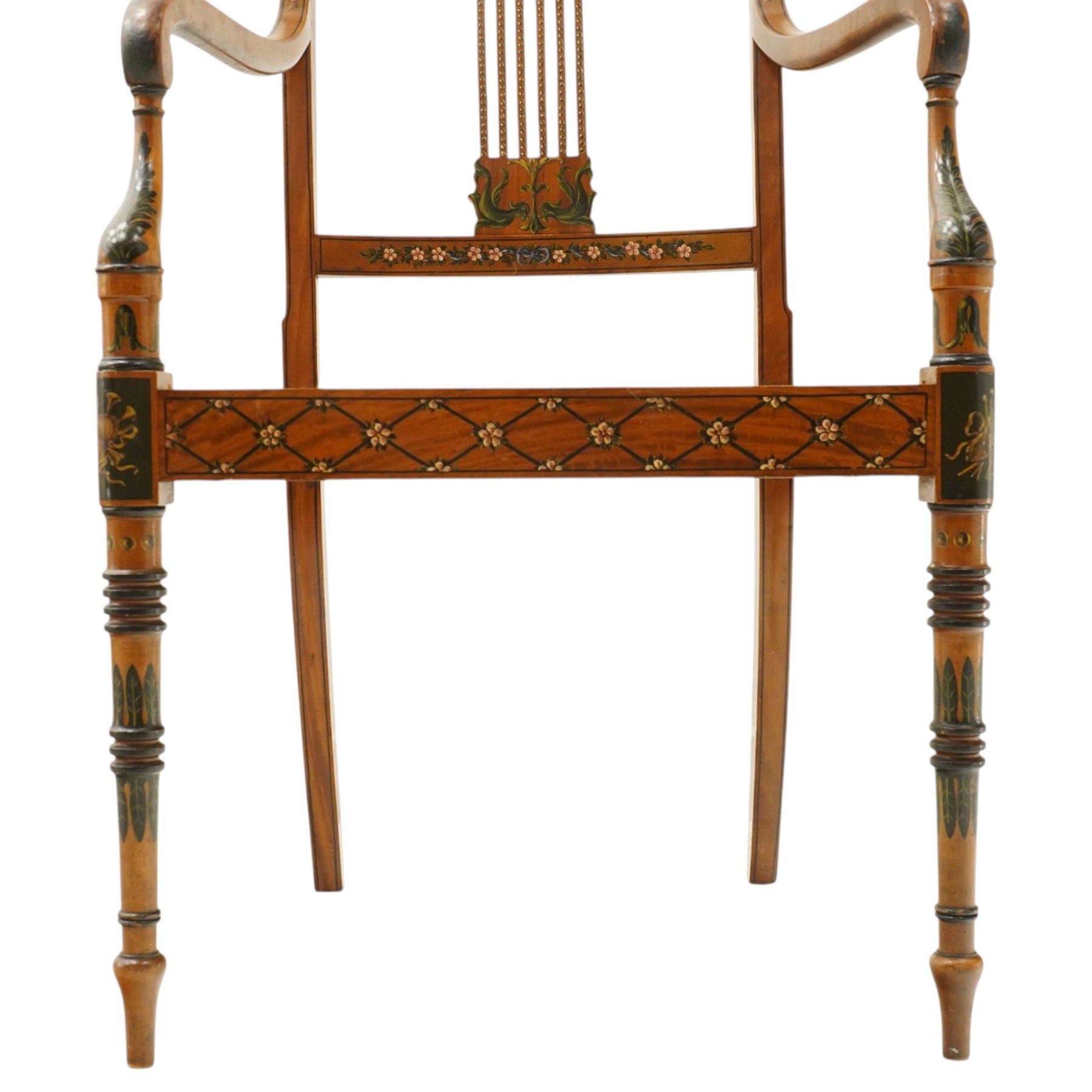 Late 19th century Adam Revival painted and parcel-ebonised satinwood open armchair, the cresting rail centred by a painted panel depicting putti holding garlands, within draped swag ornament and moulded ribbon-twists, over a pierced vertical splat with gilt beaded detail, the downswept arms and caned seat above a painted lattice and floral frieze, raised on ring-turned tapering front supports with musical instrument painted panel and acanthus leaves