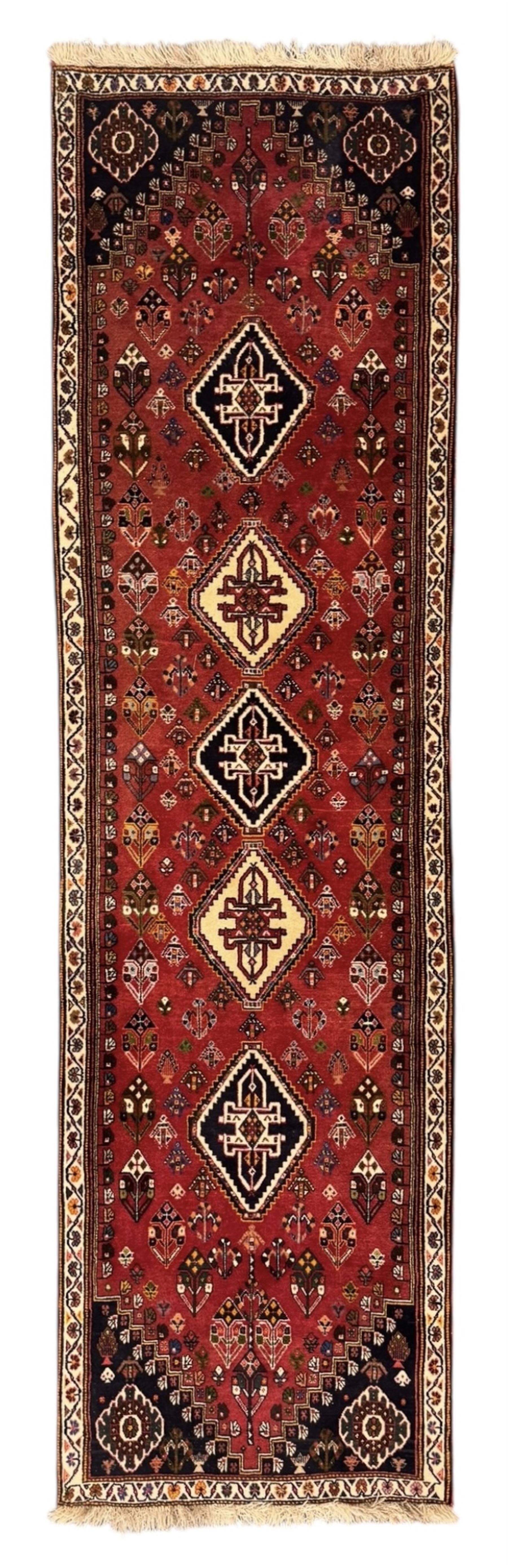 Persian Qashqai crimson ground runner, the field decorated with repeating diamond-shaped medallions flanked by angular floral motifs, the spandrels with intricate boteh designs, framed by an ivory border with stylised floral patterns and scrolling vines