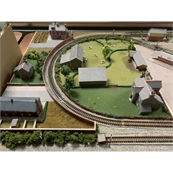 'N' gauge - wooden table-top layout of oblong form the central loop of track with sidings, station, engine shed and other buildings with the original Metcalfe kit boxes, farm with animals in fields, trees and other vegetation 122 x 61cm; and small quantity of other accessories