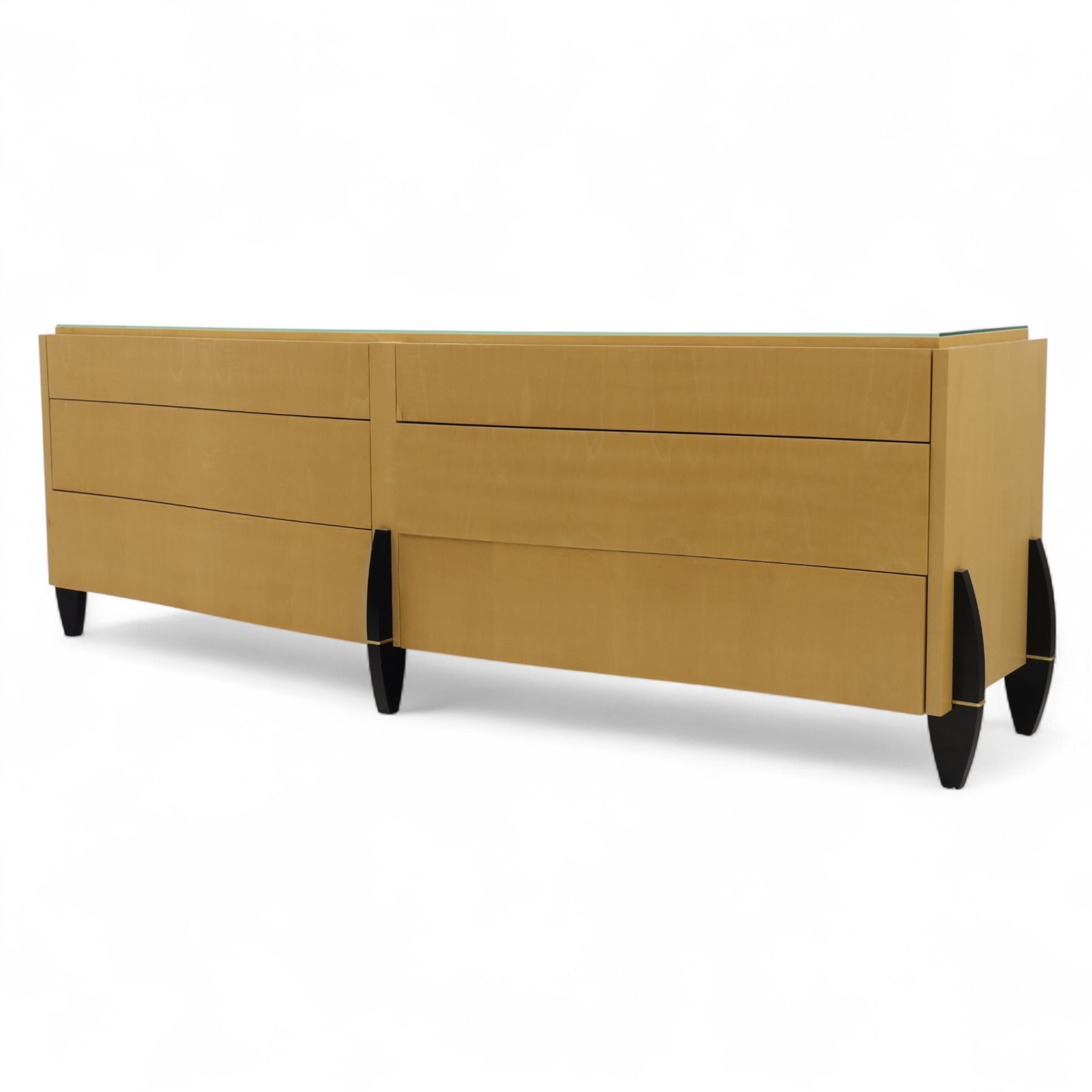 Contemporary maple veneered sideboard, serpentine glass top over six graduating Blum soft-close drawers, raised on curved black and gilt accented supports