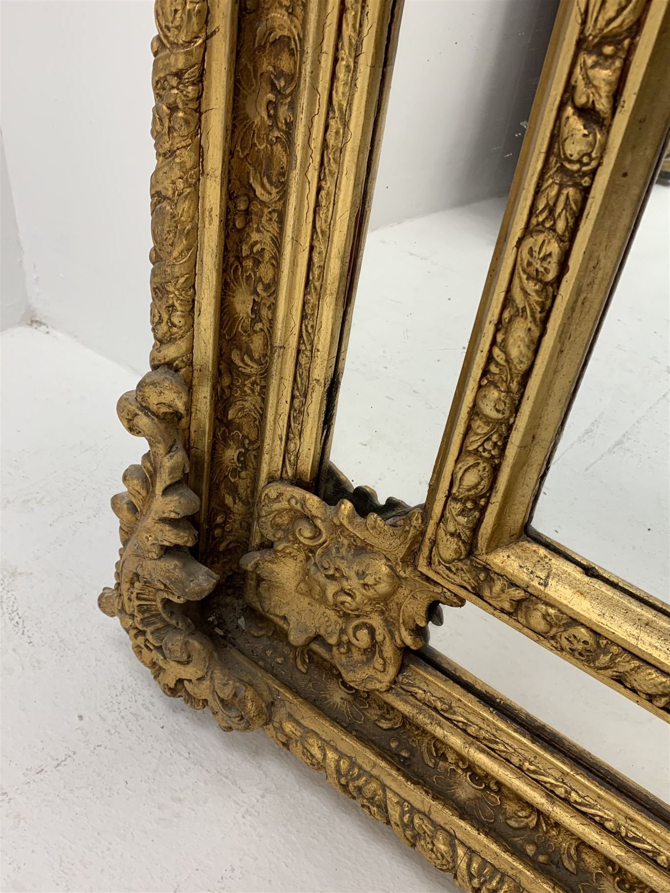 Gilt Rococo style mirror, arched top with central cartouche and oak leaf moulded pediment, floral and fruit moulded surround with segmented glass panels, bevelled central pane, c-scroll shell and acanthus leaf brackets