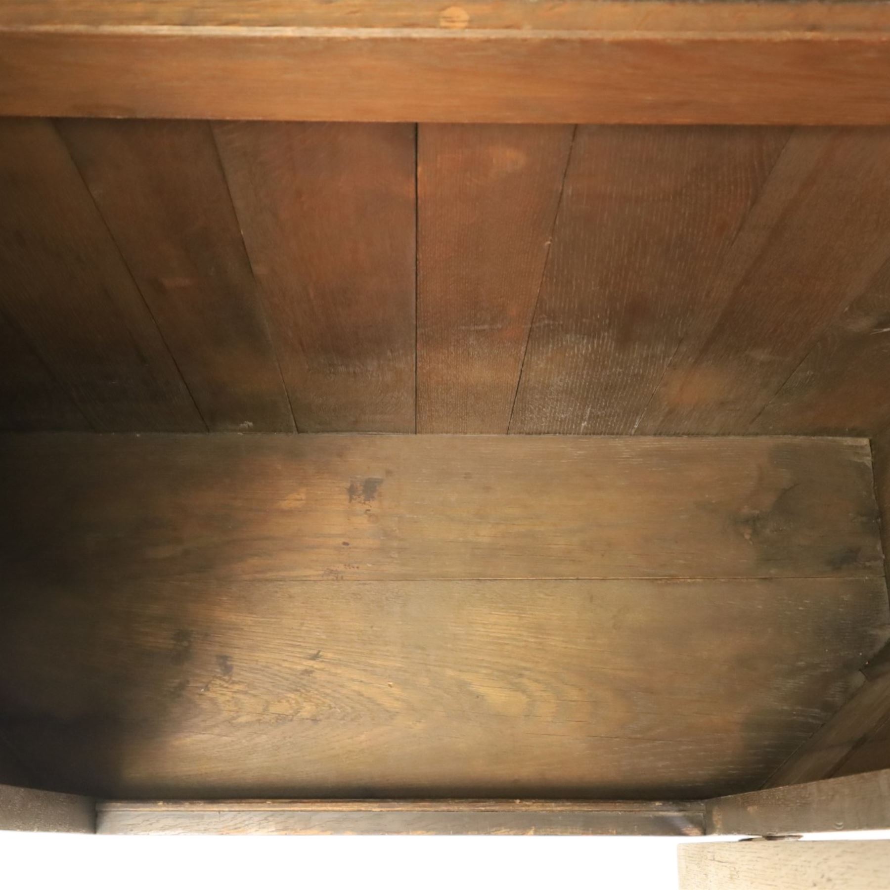 20th century dark stained oak hall robe, cantered sides enclosing a hooks and a shelf, panelled and carved sides, raised on stile supports