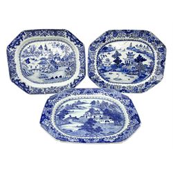 Three late 18th/early 19th century Chinese export blue and white platters, of canted form, decorated with various landscapes set with typical motifs including pagodas, bridges, and islands, within spearhead and cell diaper and foliate borders, largest example W46.5cm 
