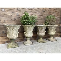 Set of four Victorian design cast stone Grecian urns, tapering form cast with figures and handles, square plinth bases
