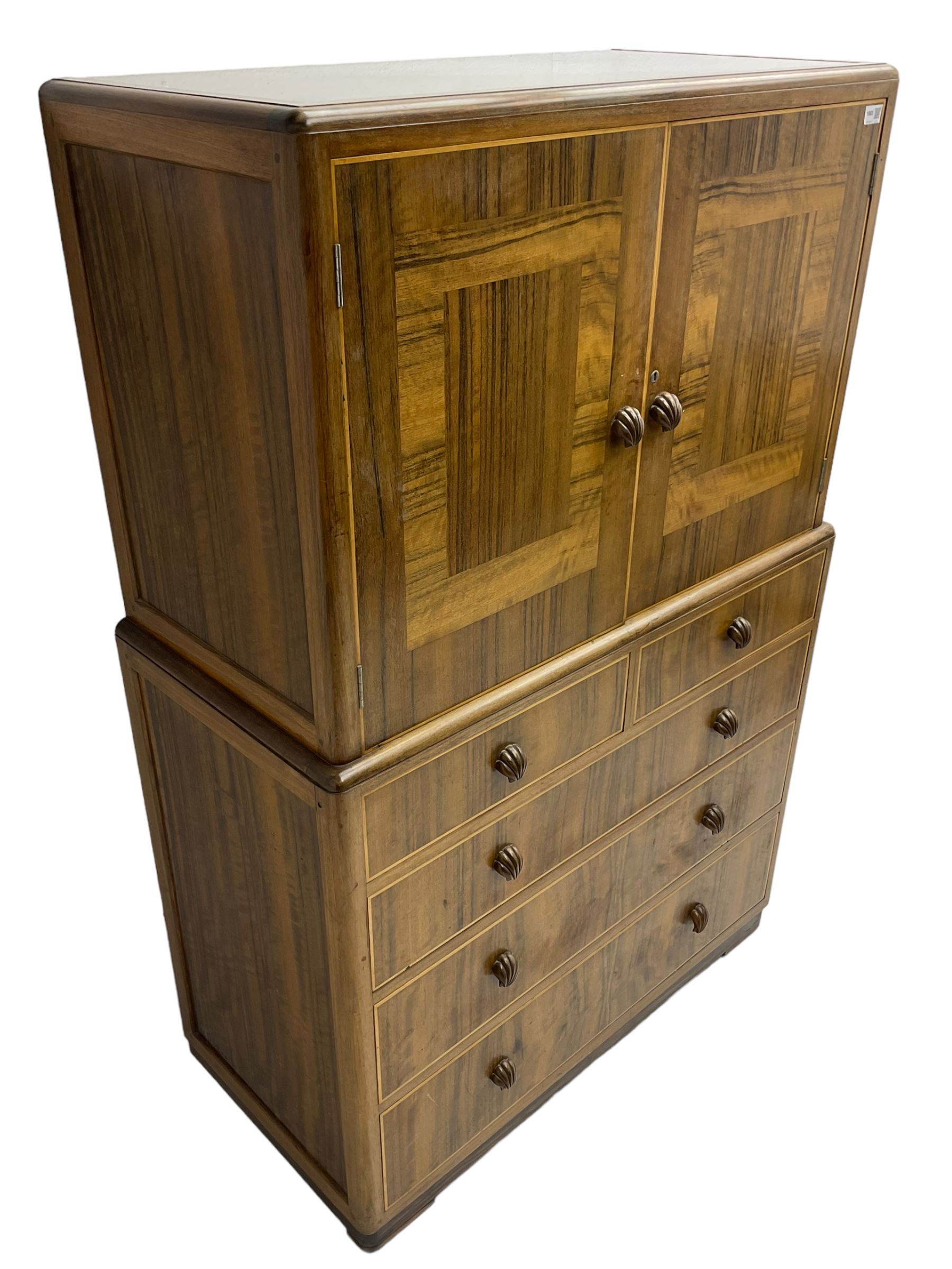 Early 20th century Art Deco walnut cocktail tallboy chest, fitted with double cupboard enclosing two shelves over two short and three long drawers, each with shell shaped handes