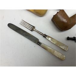 Swiss mountain hunters tobacco pipe with a horn mouthpiece, metal hinged pierced lid and brass chain, the black coated body adorned with small metal cow flowers, together with two other pipes and case, brass mounted horn, brass mounted bone box, carved mother of pearl handled knife and fork and brass jug