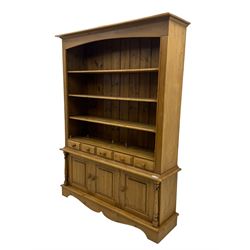 Early 20th century pine kitchen dresser, featuring a hutch with arched top over three open shelves, the base with five drawers over three cupboard doors, turned column supports flanking the doors, scalloped apron base with bracket feet