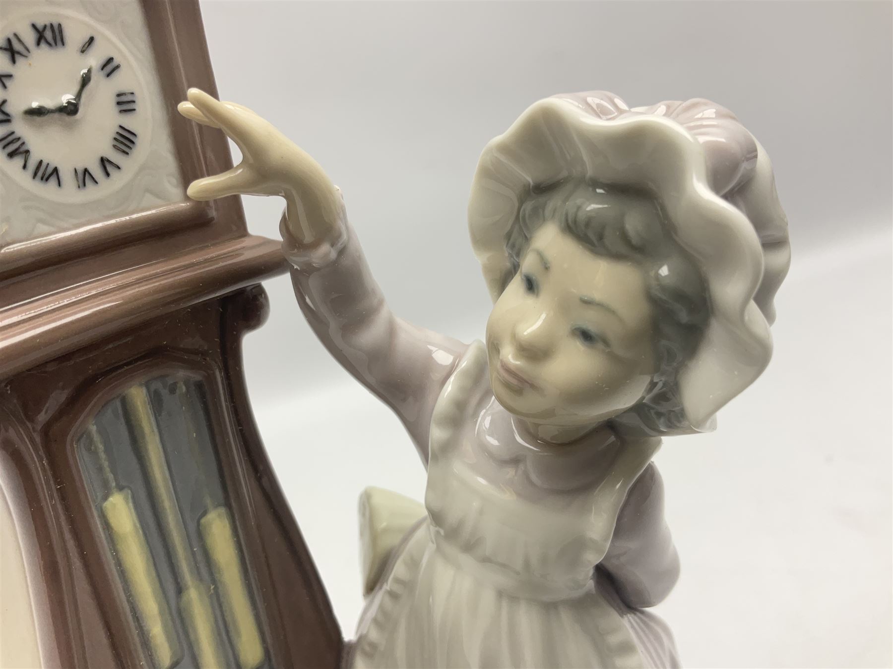 Lladro figure, Bedtime, modelled as a young girl reaching for her pet cat upon grandfather clock, sculpted by Vincente Martinez, with original box, no 5347, year issued 1986, year retired 1998, H28cm