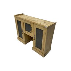Pine kitchen hutch cupboard, enclosed by three doors with metal grilles, on plinth base