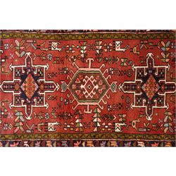 North West Persian Karajeh hand-knotted runner, madder red field with a series of shaped hexagonal medallions and cruciform motifs each enclosing geometric rosette devices linked by angular vine elements, field populated with stylized tribal ornaments, within narrow multiple borders decorated with repeating angular motifs framed by guard stripes of geometric devices, with cotton fringe ends  