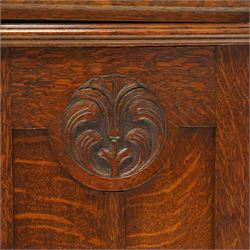 Arts and Crafts oak dresser, projecting moulded cornice above three glazed panels with coloured leaded glass floral panels, flanked by two glazed doors enclosing two adjustable shelves, open mirrored recess below with mirrored back, the base fitted with two short drawers over two central drawers flanked by carved panelled cupboard doors, ornate brass handles, raised on tapering square legs