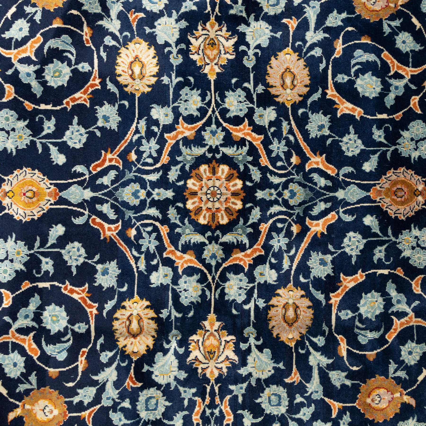 Persian Kashan carpet, navy field with an all-over design of scrolling vines, palmettes and rosettes in gold and pale blue, enclosed by multiple floral borders with stylised palmette motifs, originating from Central Iran