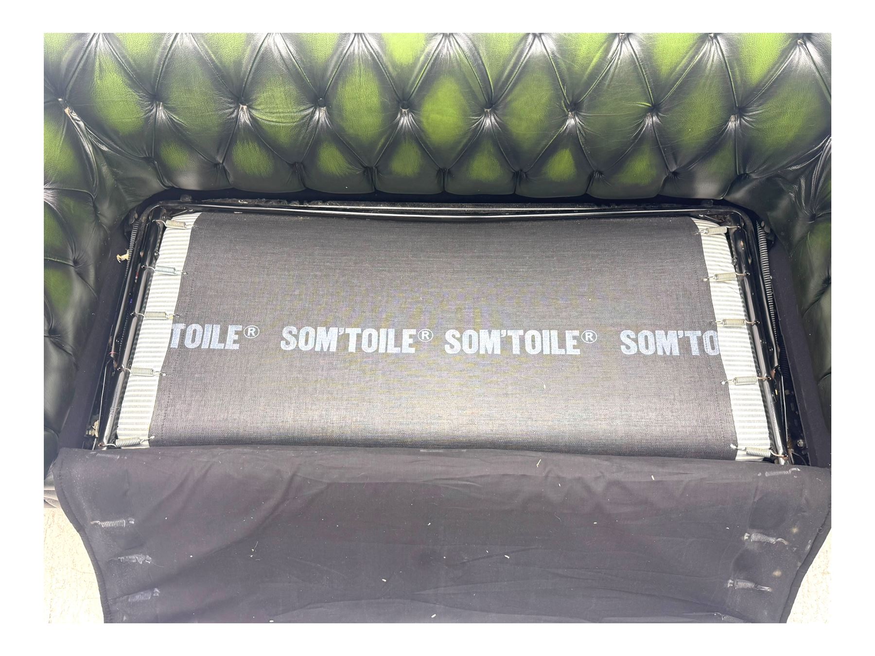 Two seat Chesterfield design sofa bed, upholstered in emerald green leather with deep-buttoned detailing, rolled arms, two loose seat cushions, and pull-out 