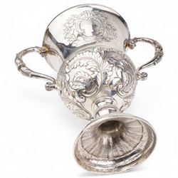 George III silver two handled campana shape cup and cover with pineapple lift, the body with cartouche surrounded by flowers above leaves and scrolls on a pedestal foot with acanthus leaf decoration H29cm London 1764, makers marks rubbed