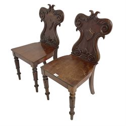 Pair 19th century walnut and mahogany hall chairs, shield back carved with c-scrolls foliage and fleur-de-lis, raised on turned and tapering supports